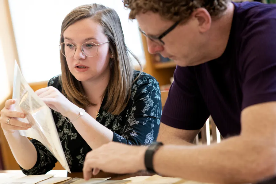 Rose McCandless studies a manuscript with RBMS Librarian Eric Johnson