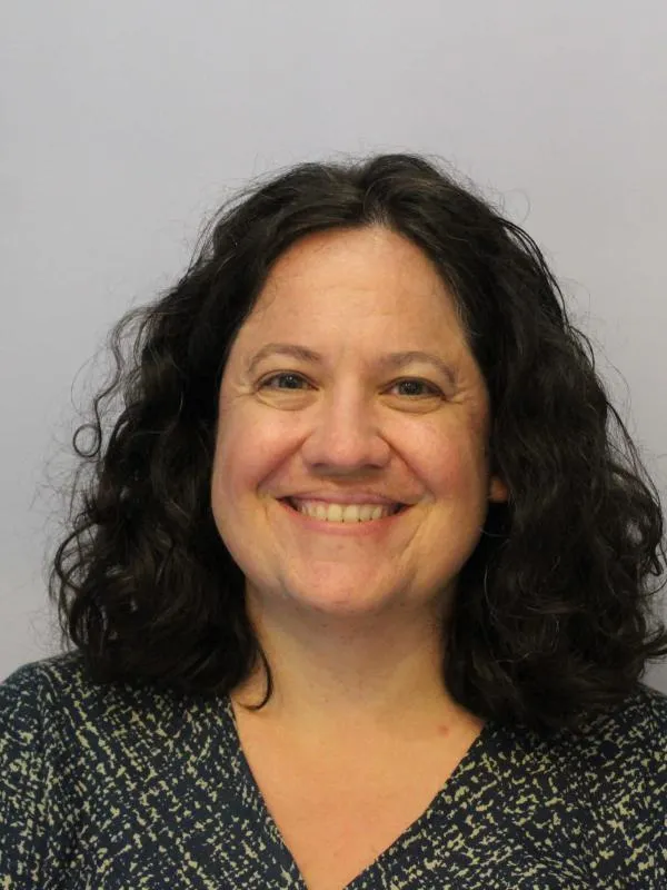 Woman with shoulder length black hair smiling for photograph 